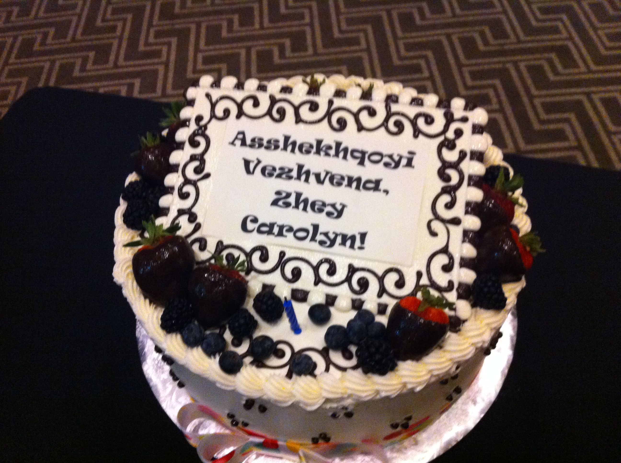 A cake with "Asshekhqoyi vezhvena, zhey Carolyn!" written on it.
